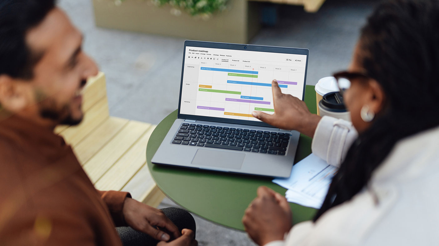 Man and woman look at computer monitor, which has a gantt chart on the screen